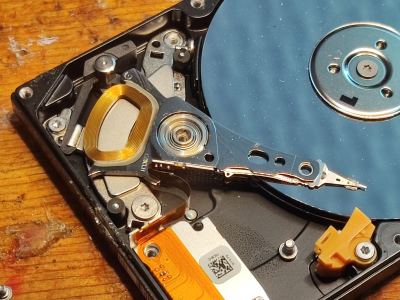 Inside View of a 2.5-Inch Hard Drive Interior of a hard drive with visible platter and head mechanism on a wooden background.