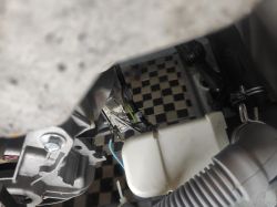 Wnętrze pralki z widocznymi elementami mechanicznymi i wtyczką.