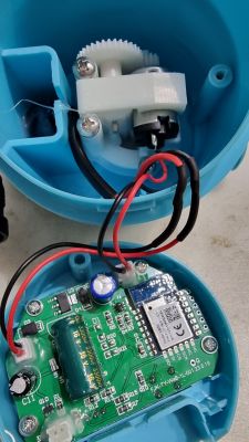 Open plastic enclosure of a device showing its interior, including a circuit board and gear mechanism.