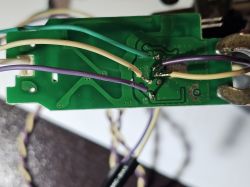 Close-up of a green PCB with soldered wires in various colors.