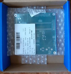 Zielona płytka PCB w otwartym pudełku z etykietą zawierającą szczegóły zamówienia.