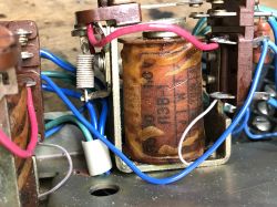 Close-up of a relay interior: large electromagnet coil with blue and red wiring on a metal base