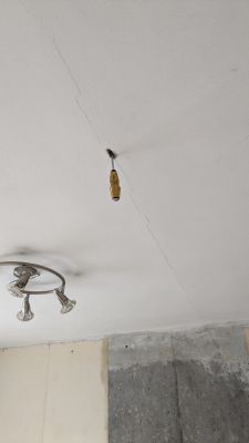 Zdjęcie sufitu z rysą i zamontowanym haczykiem do zawieszenia.