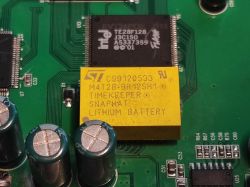 Zbliżenie na płytę główną switcha z widoczną baterią litową M4T28-BR12SH1 oraz układami scalonymi Intel i ST.
