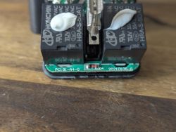 Close-up of a PCB with two black relays and white glue on the relay housings.