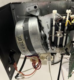 Wnętrze napędu bramy garażowej Chamberlain z widocznymi częściami elektronicznymi i mechanicznymi.