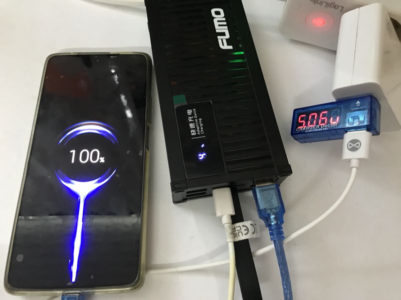 Telefon ładowany powerbankiem Fumo Pro; wyświetlacz pokazuje 100% naładowania.