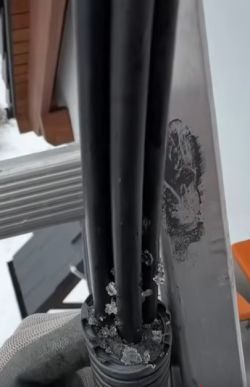 Kabel elektryczny z widoczną warstwą lodu na końcówce w zimowym otoczeniu.