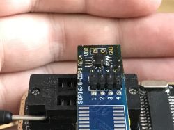 Close-up of a SOP16/8-DIP8 REV4 electronic adapter held in a hand.