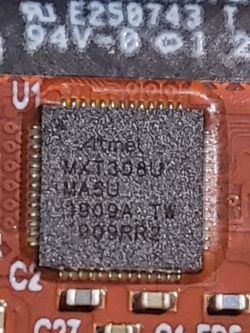 Układ scalony Atmel MXT308U na czerwonej płytce drukowanej.