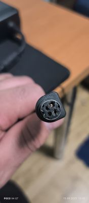 Zbliżenie na uszkodzoną 4-pinową wtyczkę zasilacza komputerowego w dłoni