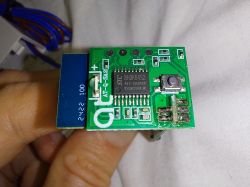 Electronic PCB with STC microcontroller and push button Close-up of a PCB with an STC chip and a push button, held between fingers.