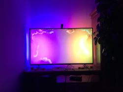 TV with active LED backlight glow in purple and yellow colors behind screen