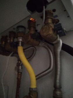 Fragment instalacji kotła gazowego z widocznymi rurami i iskrzącym elementem.