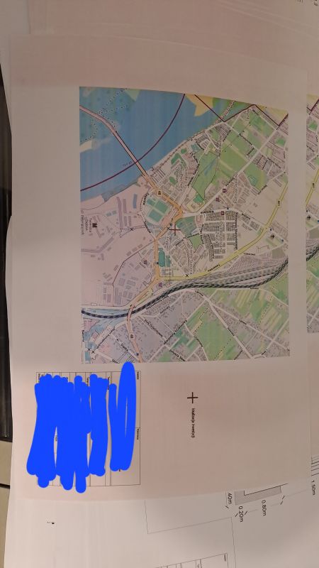 Wydruk mapy z niebieskimi i zielonymi obszarami oraz czerwonymi pasami na papierze.