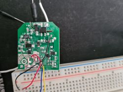 Electronic circuit board connected to a breadboard A printed circuit board with connected wires and a breadboard in the background.