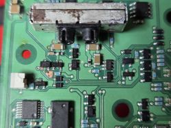 Close-up of a PCB with a metal connector at the top and surrounding SMD components