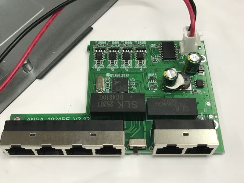 PoE switch PCB with six RJ45 ports and power components on a tabletop