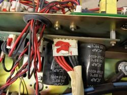 Wnętrze układu elektronicznego z widocznymi kondensatorami i przewodami połączeniowymi.