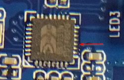 Image of an integrated circuit on a PCB with a pin marked by a red arrow.