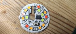 Close-up of a round LED board with multicolored LEDs and a central integrated circuit.