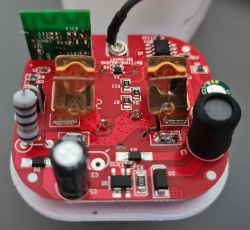 Electronic module of a smart WiFi socket with discrete components on a red circuit board.