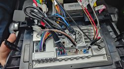 Tył nowego radia samochodowego z widocznymi złączami i kablami podłączeniowymi.