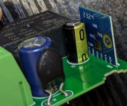Close-up of an electronic board with components, including capacitors and a module, with visible markings.