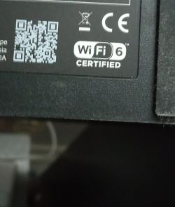 Fragment naklejki urządzenia elektronicznego z kodem QR, oznaczeniami CE, przekreślonym koszem i logo WiFi 6 CERTIFIED.