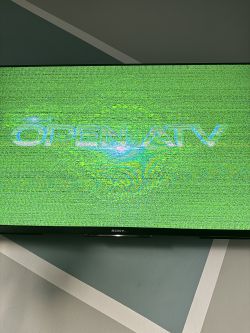 Logo OPEN ATV na ekranie telewizora jest zniekształcone i wyświetlane w zielonych kropkach.