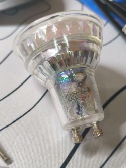 Glass LED bulb with GU10 base lying on striped white fabric