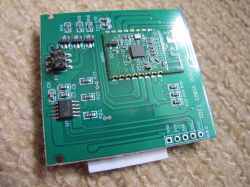 Close-up of a green PCB with a Wi-Fi module and SMD electronic components, lying on a carpet.