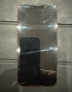 Zbliżenie telefonu z rysami na ekranie i plamką w górnej części.