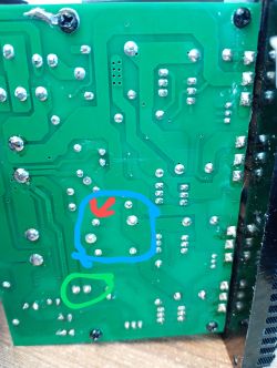 Zdjęcie zielonej płytki PCB z naniesionymi kolorowymi oznaczeniami: niebieską ramką, czerwoną strzałką oraz zielonym kółkiem.
