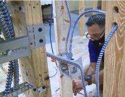 Mężczyzna pracujący przy instalacji przewodów w drewnianej konstrukcji.