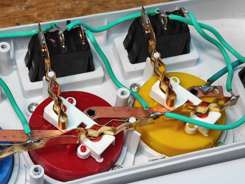 Power Strip Interior with Individual Switches Interior of a power strip with colorful sockets and green wires.