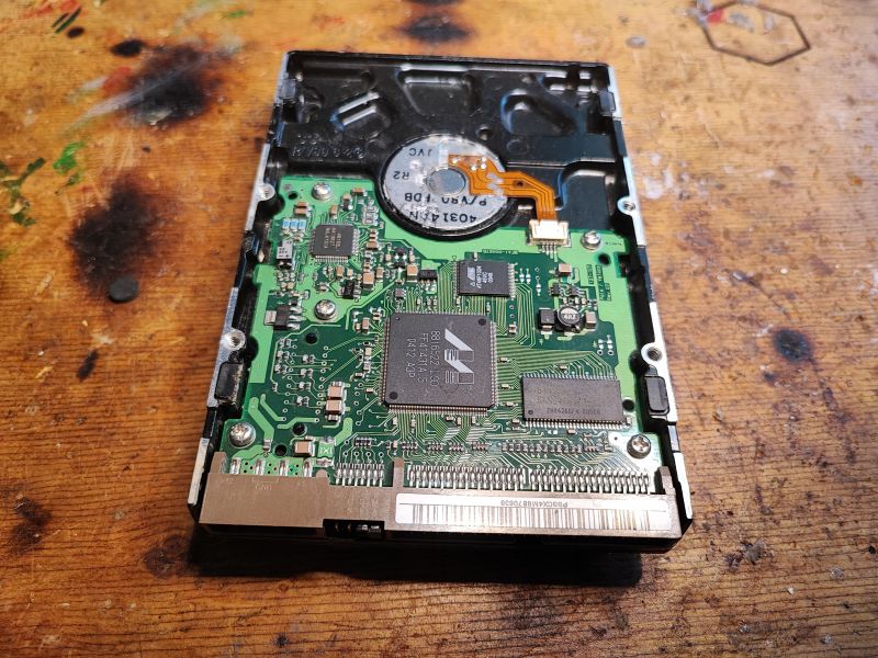 Inside View of HDD with Visible Electronics Image of the internal electronics of an old hard drive on a wooden surface.