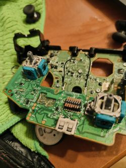Rozmontowany pad do Xboxa z widoczną płytką drukowaną i elementami elektronicznymi.