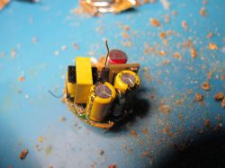 Small circuit board with yellow capacitors and other electronic components on a blue background.