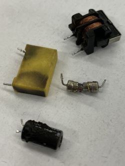 Beschädigte elektronische Bauteile mit sichtbaren Brandspuren und Verfärbungen auf hellem Hintergrund.