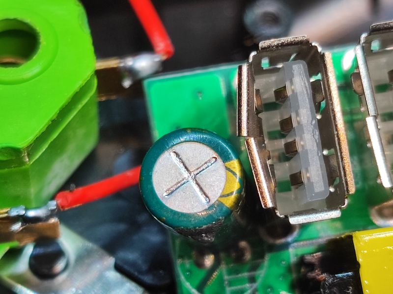 Wnętrze listwy zasilającej z wyeksponowaną elektroniką i kondensatorem.