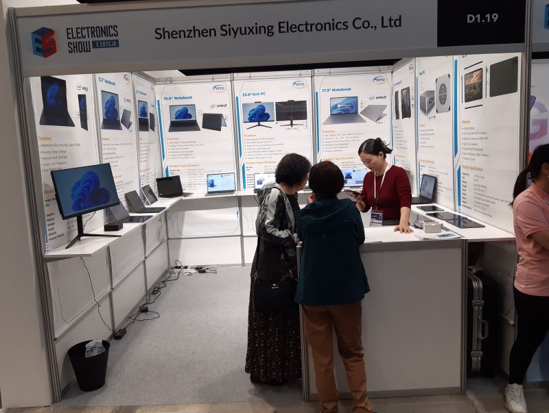 Stoisko Shenzhen Siyuxing Electronics Co., Ltd na targach elektroniki z wystawionymi laptopami i monitorami.