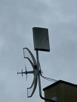 Dwie anteny zewnętrzne zamontowane na dachu budynku, skierowane w jedną stronę.