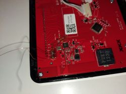 Red PCB with SMD components, QR code label, and thin wires soldered to test pads