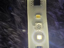 Nahaufnahme einer Platine mit adressierbaren LEDs, mit sichtbarem Chip und Metallkontakten.