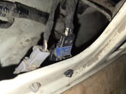 Zbliżenie na wiązkę przewodów i niepodłączone kostki elektryczne w bagażniku samochodu