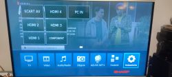 Ekran telewizora SHARP LC-39LE652V z menu wejść i kolorystycznymi zakłóceniami.