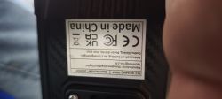 Odwrócona tabliczka znamionowa na czarnym urządzeniu z napisem „Made in China” i znakami CE, FCC, UKCA
