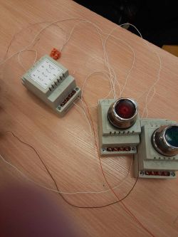 Elementy elektryczne, stycznik z przewodami i dwa przyciski na stole.