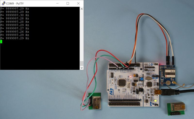 Płytka STM32 podłączona do modułów elektronicznych oraz ekran komputera z wynikami pomiarów częstotliwości.